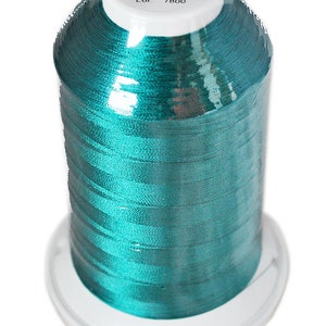 May include: A spool of teal-colored thread labeled "RHEINGOLD" with the following information: "Made in Germany", "Nr. 40 5000m", "100% Polyester filementes", "Art. Nr. P914", "Col. 5879", "Lot. 7800".