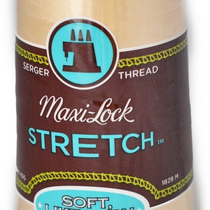 Peut inclure: Une bobine de fil à coudre beige Maxi-Lock Stretch pour surjeteuse, étiquetée "Soft, Like Yarn" et "Textured Nylon". La bobine mesure 1828 mètres de long.