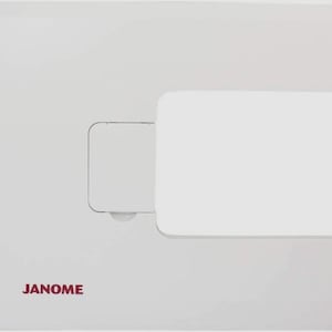 May include: White sewing machine extension table with a Janome logo. The table is rectangular with a rounded edge on the right side. There is a small rectangular opening on the left side of the table.