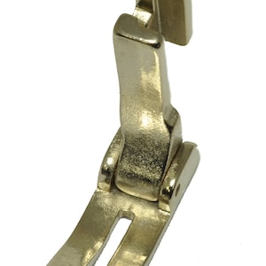 May include: A gold-colored sewing machine foot with a split needle plate and a curved shank.