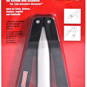 Puede incluir: Un afilador de diamante compacto para cuchillos y tijeras, en un paquete rojo. El afilador es negro y plateado, con el texto "Compact Diamond Sharpener" y "Lifetime Guarantee".