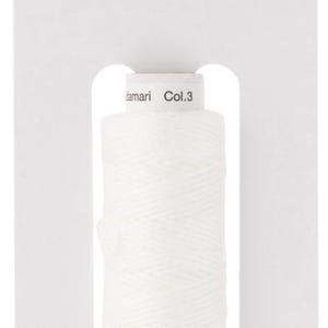 Op de afbeelding: Witte sashiko garen spoel met het label "hidamari Sashiko &" en "Col.3" op een witte kaart met de tekst "cosmio LECIEN CORPORATION".