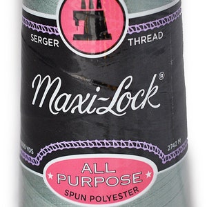 以下が含まれることがあります： 淡い緑色のMaxi-Lockオーバーロック糸のスプール。ブランド名、ミシンイラストのピンク色の円、そして「All Purpose Spun Polyester」の文字がラベルに表示されています。