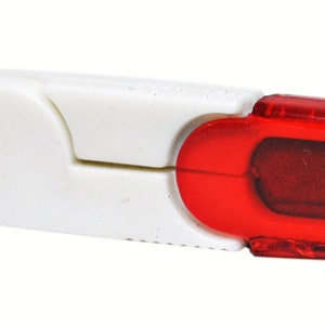 May include: A white and red plastic thread cutter with a small red circle on the handle.