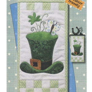 Könnte beinhalten: Ein grüner und weißer Patchwork-Quiltblock mit einem grünen Leprechaun-Hut, einem Schmetterling und Kleeblättern. Der Block ist 15,24 cm x 30,48 cm groß und trägt die Aufschrift "Lucky Hat".