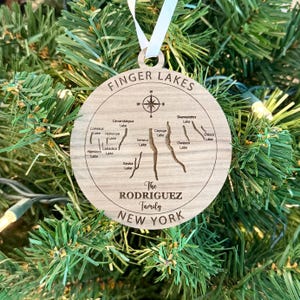 May include: A wooden ornament shaped like a map of the Finger Lakes region of New York State. The ornament is personalized with the text "The Rodriguez Family".