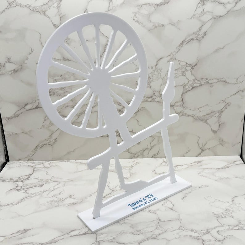 May include: White wooden spinning wheel cutout with a base that reads "Laura's New" and "January 25, 2023".