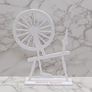 May include: White wooden spinning wheel cutout with the name "Aurora Leanne" written on the base.