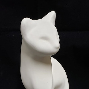 May include: White ceramic cat figurine with a stylized design. The cat is sitting with its head turned to the side.