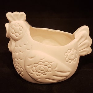 Könnte beinhalten: Weißer Keramik-Hühnertopf mit einem detaillierten Blumendesign. Der Topf hat eine große Öffnung zum Pflanzen und einen kleinen Schnabel.