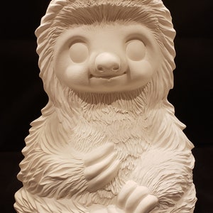 Peut inclure: Figurines de paresseux en céramique blanche avec une texture de fourrure détaillée. Le paresseux est assis les bras croisés devant lui.