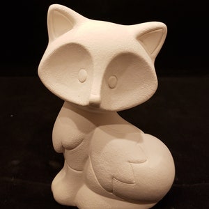 Peut inclure: Figurines en céramique blanche d'un renard assis avec sa queue enroulée autour de son corps. Le renard a un design simple et cartoon avec de grands yeux et un petit nez.