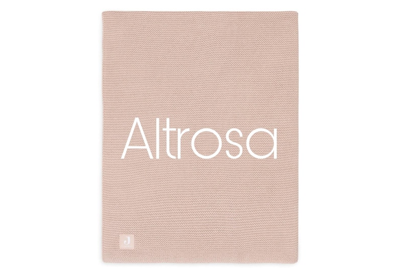 Op de afbeelding: Een rechthoekige, oudroze gebreide deken met een fijne, gelijkmatige ribbelsteek textuur. Het woord Altrosa is in grote, witte, schreefloze hoofdletters in het midden gedrukt. Een klein, vierkant label met de letter J is zichtbaar.