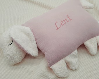 Peut inclure: Une peluche en forme de mouton avec un corps rectangulaire rose poudré et un tissu texturé crème pour la tête, les oreilles et les pattes. Le prénom Leni est brodé en écriture cursive rose au centre du corps rose de la peluche.