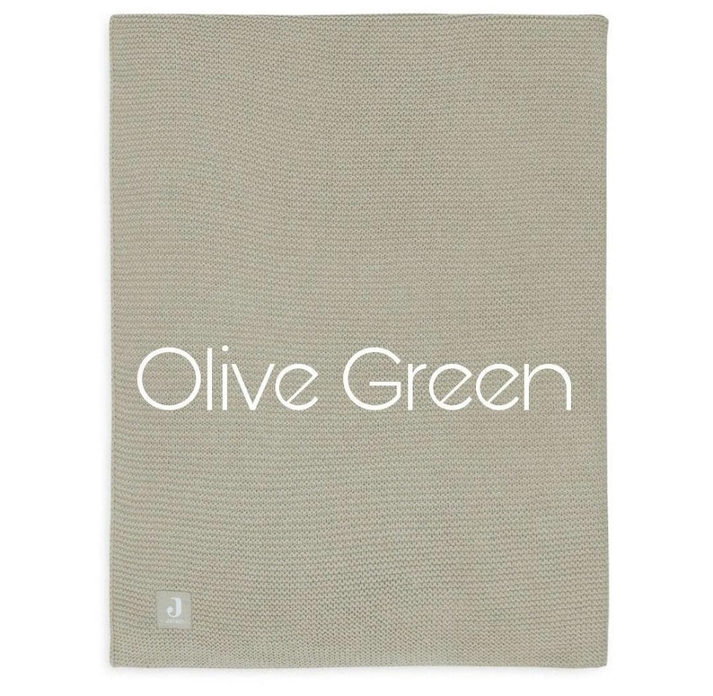 Puede incluir: Manta de punto verde oliva. La manta es de color liso con un aspecto texturizado. Las palabras "Olive Green" est&aacute;n escritas en blanco en la manta. Una peque&ntilde;a etiqueta con una "J" est&aacute; en la esquina inferior izquierda.