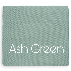Puede incluir: Una manta cuadrada y doblada en color verde ceniza apagado. La manta tiene un patr&oacute;n de tejido texturizado. Las palabras "Ash Green" est&aacute;n impresas en blanco en la parte delantera de la manta.