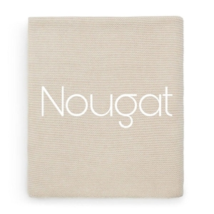 Puede incluir: Una manta de punto beige doblada con la palabra "Nougat" en escritura blanca en la parte delantera. La manta tiene un aspecto texturizado y est&aacute; hecha de un material suave. El color neutro la hace adecuada para varios estilos de decoraci&oacute;n del hogar.