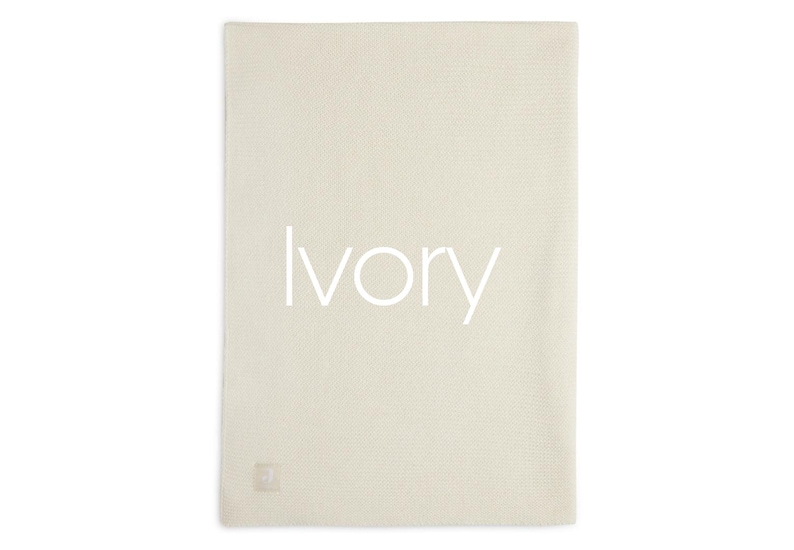 Op de afbeelding: Een rechthoekig ivoorkleurig textiel met een fijngebreide textuur. Het woord Ivory is in een strak, wit schreefloos lettertype in het midden gedrukt. Een klein, vierkant, lichtgekleurd stoffen label is bevestigd aan de linkerbenedenhoek.