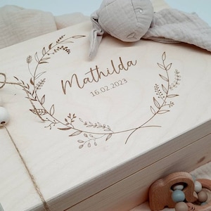 Könnte beinhalten: Eine Holzkiste mit einem floralen Kranzdesign und dem Namen "Matilda" auf dem Deckel graviert. Das Datum "16.02.2023" ist ebenfalls auf dem Deckel graviert.
