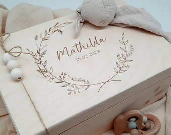 May include: A wooden keepsake box with a floral wreath design and the name "Matilda" engraved on the lid. The date "16.02.2023" is also engraved on the lid.