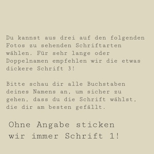 Op de afbeelding: Een beige informatiekaart met zwarte tekst in het Duits. De tekst legt de opties voor lettertypekeuze voor borduurwerk uit, waarbij wordt opgemerkt dat lettertype 3 wordt aanbevolen voor lange namen en lettertype 1 de standaard is.