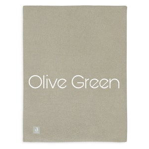 Puede incluir: Manta de punto verde oliva. La manta es de color verde oliva liso con un patr&oacute;n de punto texturizado. Las palabras "Olive Green" est&aacute;n impresas en blanco en la manta. Una peque&ntilde;a etiqueta blanca est&aacute; en la esquina inferior.