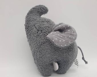 Op de afbeelding: Grijs pluche olifantenspeelgoed met een wit gestippeld oor. De olifant heeft een kleine staart en een wit label aan zijn poot.