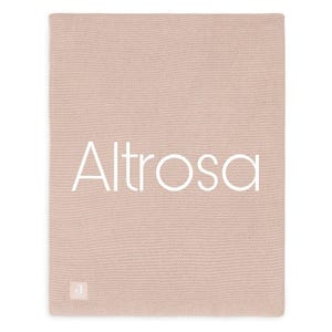 Puede incluir: Una manta de punto rosa p&aacute;lido con la palabra "Altrosa" en blanco en el centro. La manta tiene una superficie texturizada y una peque&ntilde;a etiqueta blanca con una "J" en la esquina inferior izquierda.