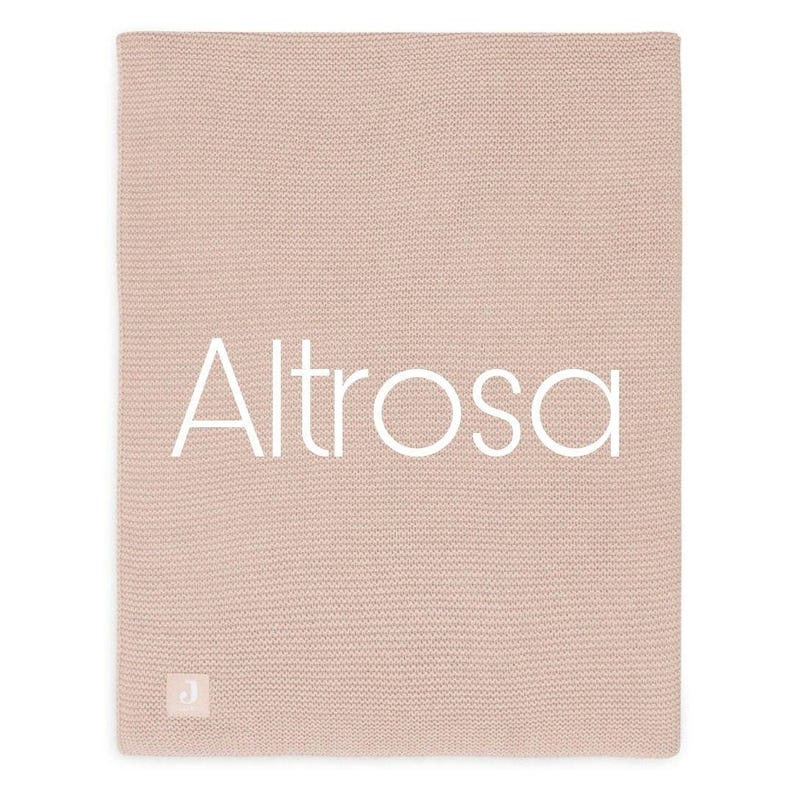Puede incluir: Una manta de punto rosa p&aacute;lido con la palabra "Altrosa" en blanco en el centro. La manta tiene una superficie texturizada y una peque&ntilde;a etiqueta blanca con una "J" en la esquina inferior izquierda.