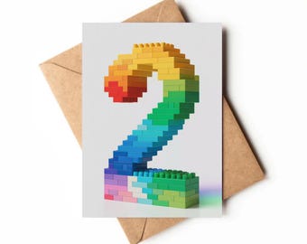Puede incluir: Tarjeta de felicitación con el número dos hecho con bloques de construcción de colores. El número tiene un degradado de colores, de rojo a verde, sobre un fondo blanco.