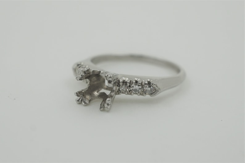 Puede incluir: Una montura de anillo de plata con un dise&ntilde;o delicado y peque&ntilde;os diamantes engastados a lo largo de la banda.