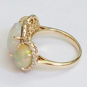 May include: A gold ring with two opal gemstones and a diamond halo setting. The ring is marked "DAVID KORD 14K" on the inside band.