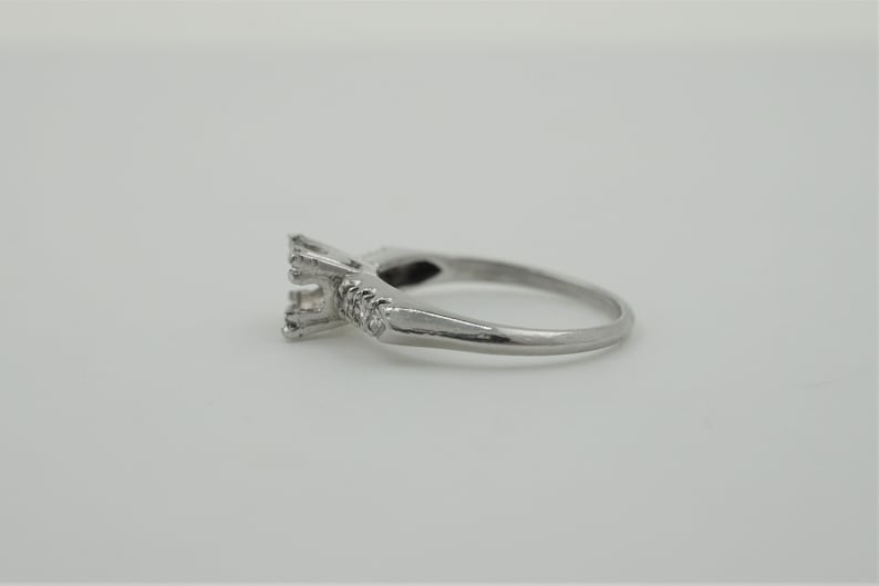Puede incluir: Un anillo de compromiso de plata con una montura de garras para una piedra central y peque&ntilde;os diamantes en la banda.