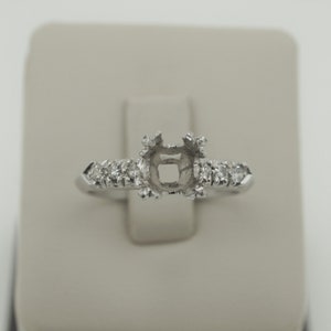 Puede incluir: Un engaste de anillo de plata con una piedra central cuadrada y peque&ntilde;os diamantes redondos en la banda.