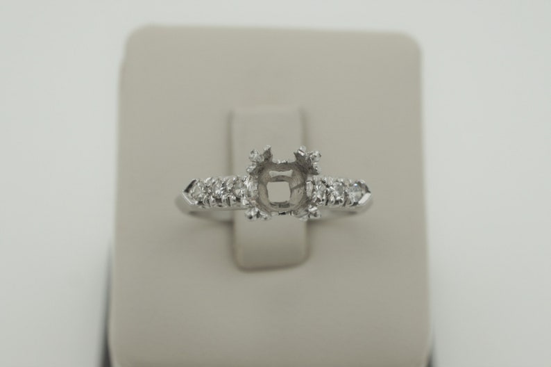 Puede incluir: Un engaste de anillo de plata con una piedra central cuadrada y peque&ntilde;os diamantes redondos en la banda.