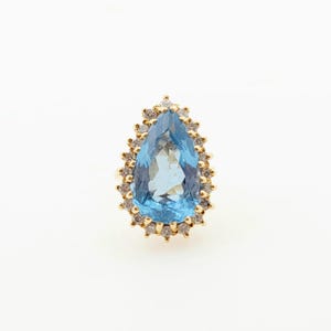 Hermoso anillo vintage de 1980 hecho a mano en oro amarillo macizo de 14 quilates con topacio azul natural en forma de pera y halo de diamantes naturales de talla redonda.