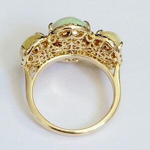May include: A gold ring with three opal stones set in a delicate filigree design.