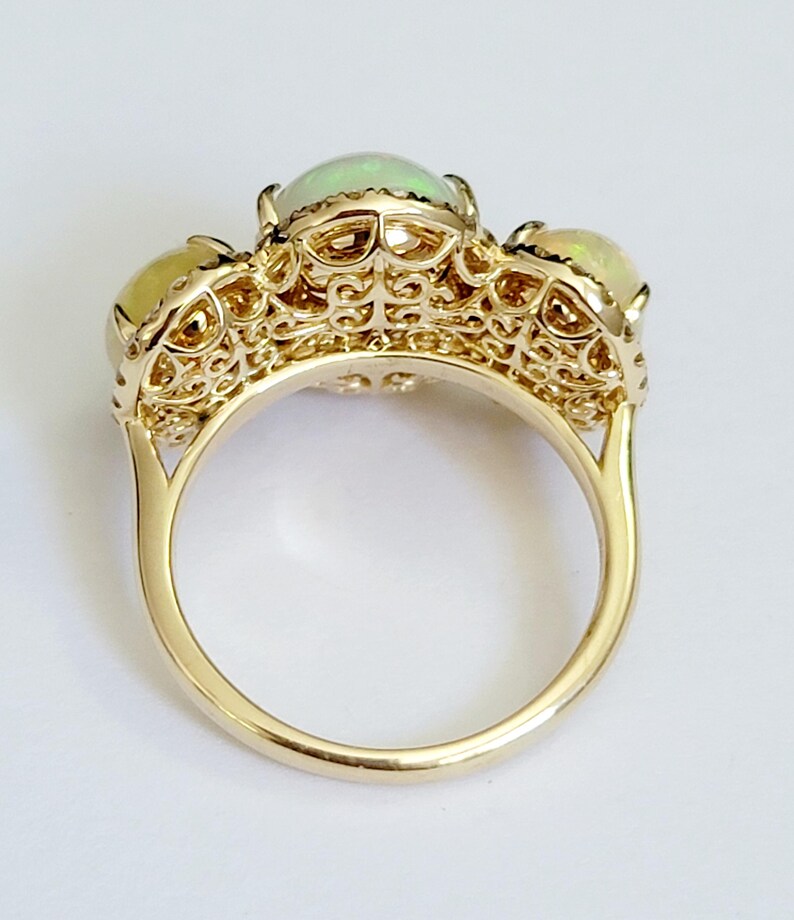 May include: A gold ring with three opal stones set in a delicate filigree design.