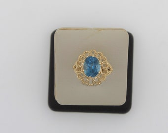 May include: A gold ring with a blue oval gemstone set in a delicate filigree design.