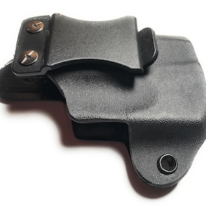Puede incluir: Funda de pl&aacute;stico negro con un clip para cintur&oacute;n y dos tornillos plateados. La funda tiene una superficie texturizada y un peque&ntilde;o agujero en la parte inferior.