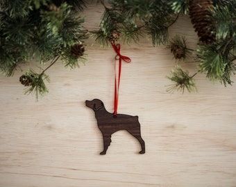 May include: A brown wooden Christmas ornament shaped like a Brittany dog with a red ribbon attached.