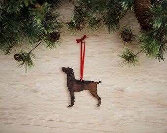 May include: A wooden dog ornament with a red ribbon hanging from a brown wooden surface.