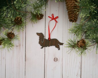 May include: Wooden dachshund ornament with a red ribbon hanging from a white wood background.