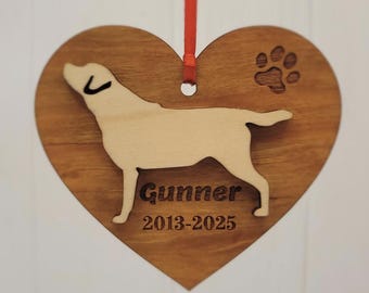 May include: Wooden heart-shaped ornament with a dog silhouette and paw print. The ornament has a red ribbon for hanging. The dog's name, "Gunner," and the years "2013-2025" are engraved on the heart.