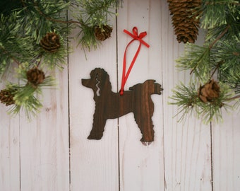 May include: A wooden Christmas ornament shaped like a poodle, painted brown with a red ribbon attached.