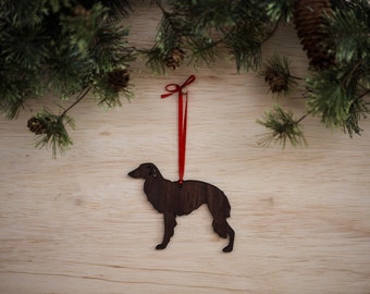 May include: A wooden Christmas ornament shaped like a black and brown dog with a red ribbon attached.