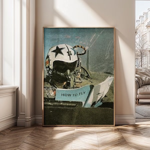May include: Framed vintage-style print featuring a pilot's helmet with a star emblem and the text "HOW TO FLY" on a blue background. The artwork has a distressed, aged appearance, with a gold frame.