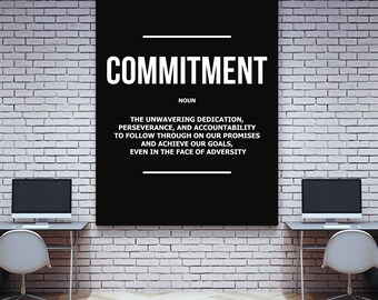 May include: A black rectangular wall art piece with the word "COMMITMENT" in large white letters. Below, the definition of commitment is written in white text. The artwork hangs on a white brick wall.