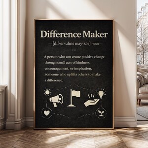 May include: A framed black and white print with the words "Difference Maker" and its pronunciation. The definition of "Difference Maker" is written below, along with several small illustrations of a megaphone, flag, lightbulb, and heart.