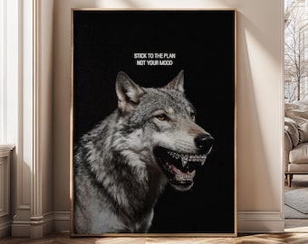 Op de afbeelding: Een ingelijste kunstdruk met een grijze wolf met een beugel, tegen een zwarte achtergrond. De tekst "STICK TO THE PLAN NOT YOUR MOOD" staat bovenaan. Het kunstwerk zit in een gouden lijst.